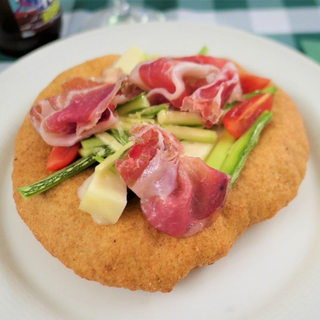 Focaccia fritta con prosciutto, formaggio, asparagi e pomodori freschi.